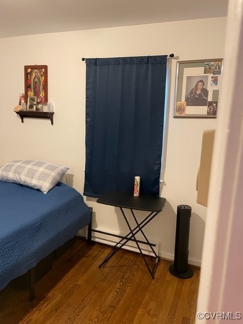 bedroom featuring dark wood-type flooring and a baseboard heating unit