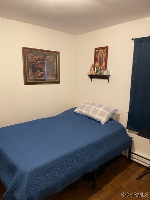 bedroom with dark hardwood / wood-style flooring and a baseboard radiator