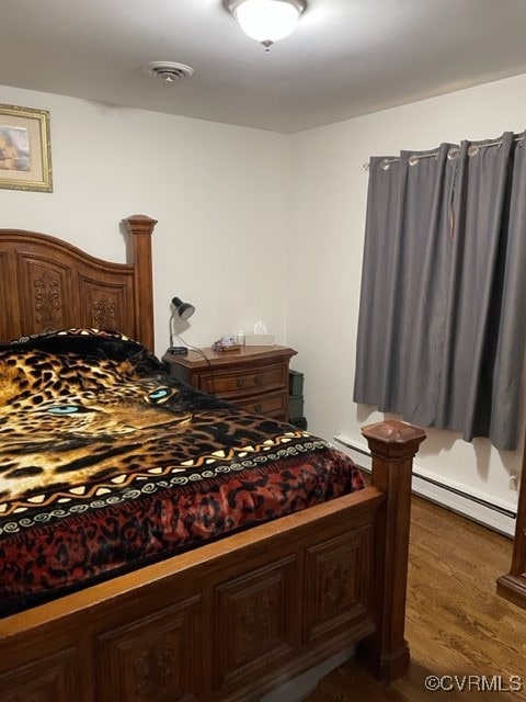 bedroom with dark wood-type flooring and a baseboard radiator