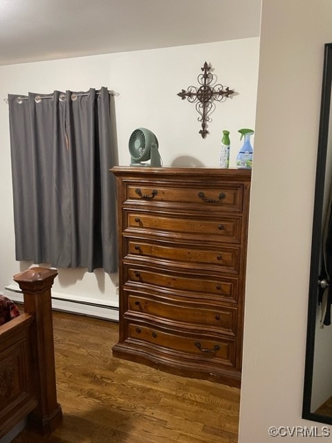 bedroom with dark wood-type flooring and a baseboard heating unit