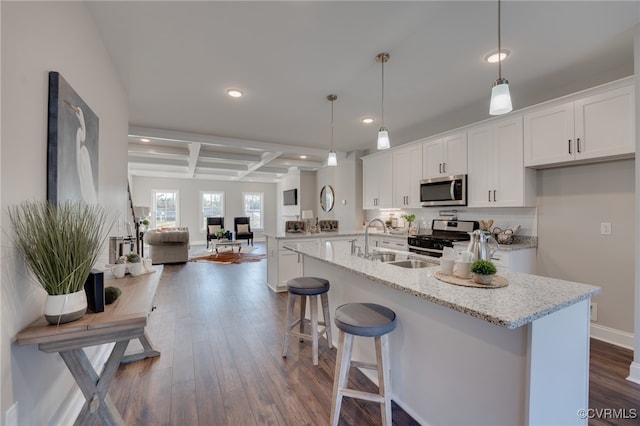 kitchen with appliances with stainless steel finishes, dark hardwood / wood-style flooring, sink, pendant lighting, and white cabinets