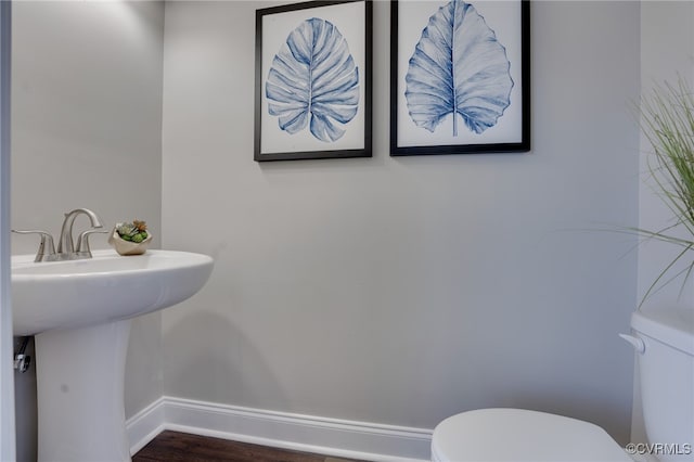 bathroom with toilet, wood-type flooring, and sink