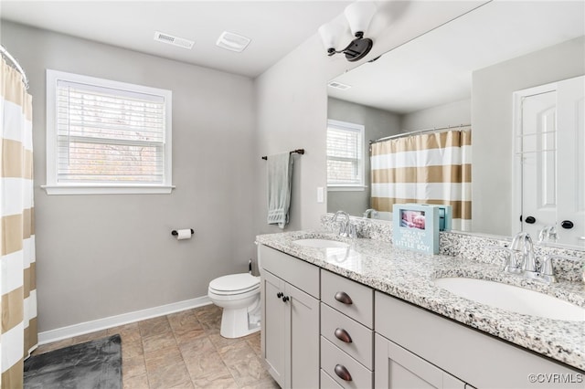 bathroom featuring vanity, a healthy amount of sunlight, and toilet