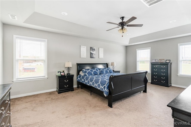 bedroom with a raised ceiling, ceiling fan, and light colored carpet