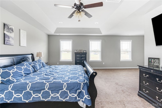 carpeted bedroom with a raised ceiling and ceiling fan