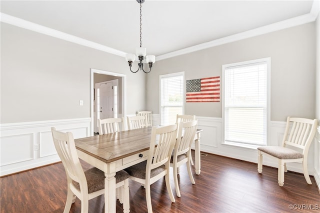 dining area with dark hardwood / wood-style flooring, ornamental molding, and a notable chandelier