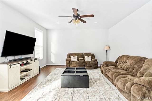 living room featuring ceiling fan and dark hardwood / wood-style flooring