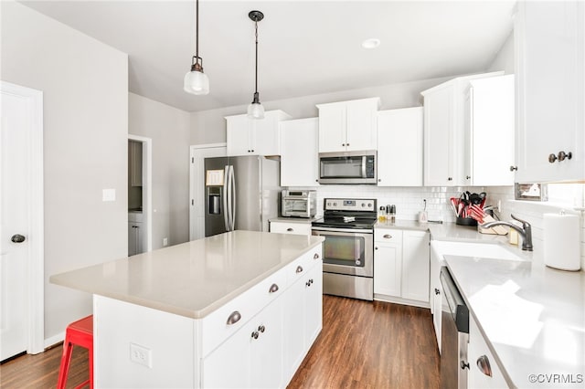 kitchen with white cabinets, sink, appliances with stainless steel finishes, a kitchen island, and dark hardwood / wood-style flooring