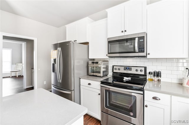 kitchen with backsplash, white cabinetry, dark wood-type flooring, and appliances with stainless steel finishes