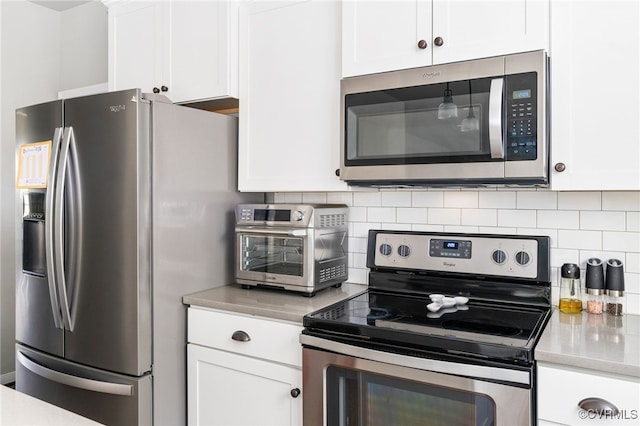 kitchen with tasteful backsplash, white cabinets, and stainless steel appliances