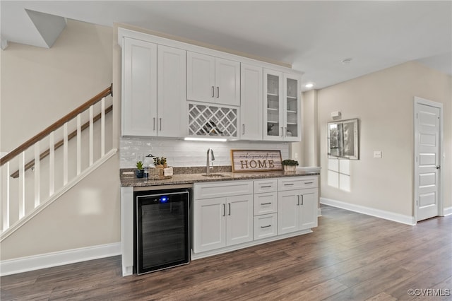 kitchen featuring dark stone counters, white cabinets, sink, dark hardwood / wood-style flooring, and beverage cooler