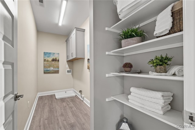 laundry area with electric dryer hookup, cabinets, hookup for a washing machine, and light hardwood / wood-style floors