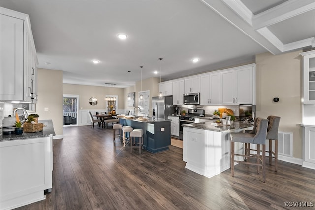 kitchen with stainless steel appliances, a kitchen island, dark hardwood / wood-style flooring, a breakfast bar area, and white cabinets