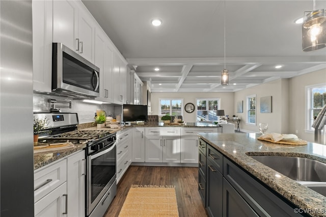 kitchen featuring white cabinets, stainless steel appliances, hanging light fixtures, and coffered ceiling