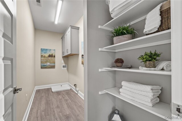 washroom featuring washer hookup, light hardwood / wood-style floors, cabinets, and hookup for an electric dryer