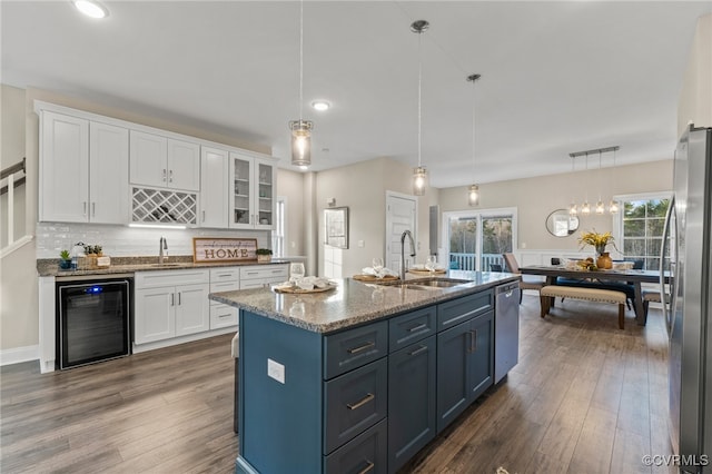 kitchen featuring appliances with stainless steel finishes, sink, white cabinets, wine cooler, and hanging light fixtures