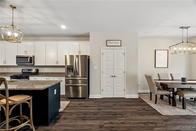 kitchen featuring light stone countertops, stainless steel appliances, pendant lighting, a kitchen bar, and white cabinets