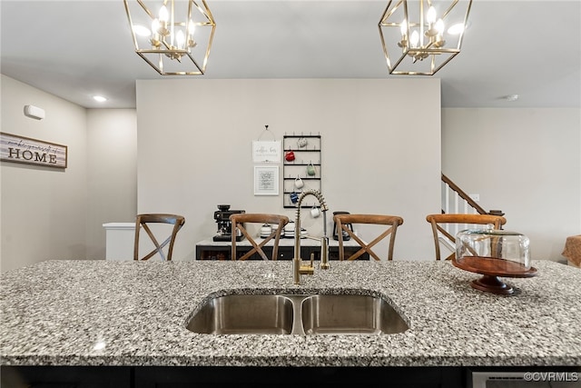 kitchen with light stone countertops, sink, decorative light fixtures, and a notable chandelier