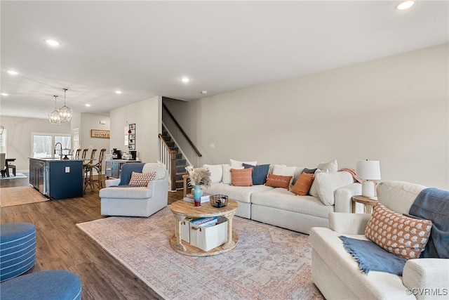 living room featuring sink, dark wood-type flooring, and an inviting chandelier