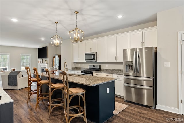 kitchen with dark wood-type flooring, a center island with sink, white cabinets, and stainless steel appliances