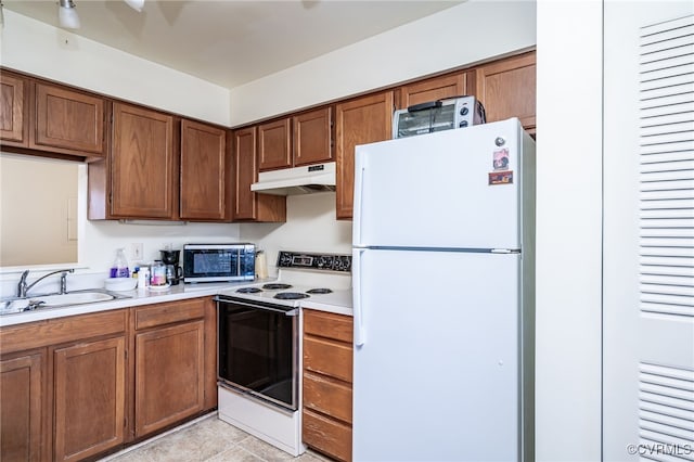 kitchen featuring light tile patterned flooring, white appliances, and sink