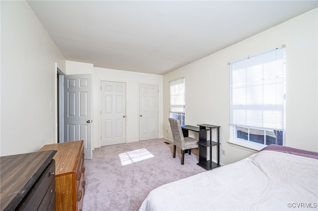 bedroom with multiple windows and light carpet