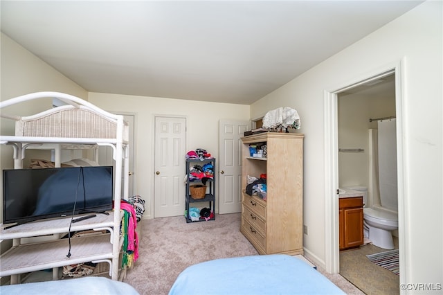 bedroom featuring connected bathroom and light colored carpet