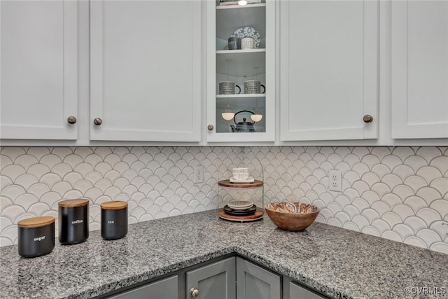 kitchen with white cabinetry, light stone counters, and tasteful backsplash