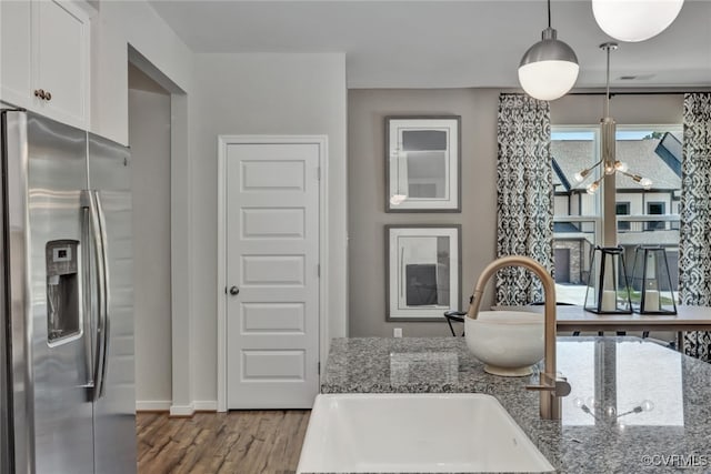 kitchen with sink, hanging light fixtures, stainless steel refrigerator with ice dispenser, white cabinets, and stone countertops