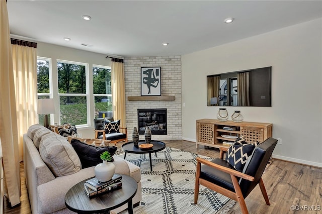 living room with wood-type flooring and a brick fireplace