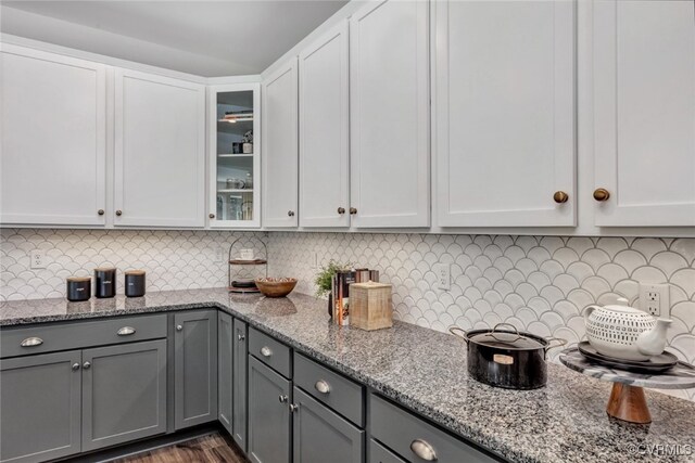 kitchen featuring tasteful backsplash, light stone countertops, and white cabinets