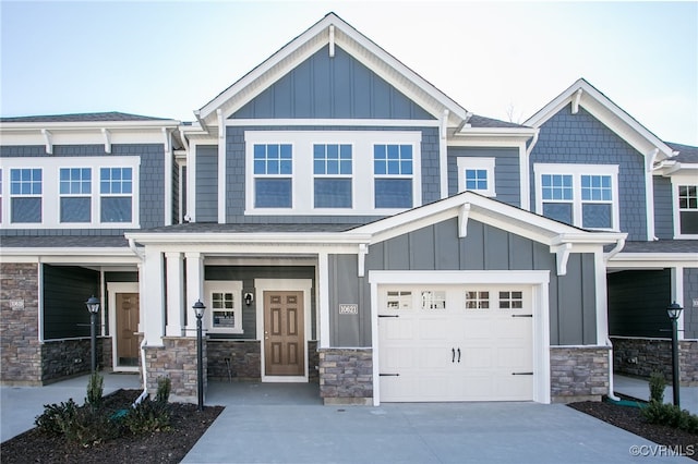 view of front of property featuring stone siding, board and batten siding, concrete driveway, and an attached garage