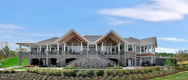 rear view of property with stairway, stone siding, a garage, and covered porch