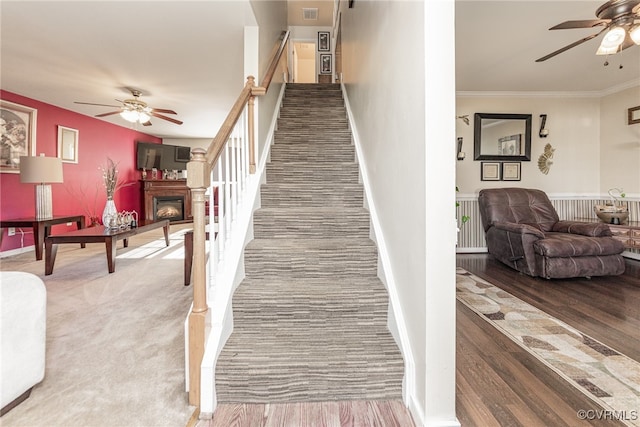 stairs with ceiling fan, wood-type flooring, and ornamental molding