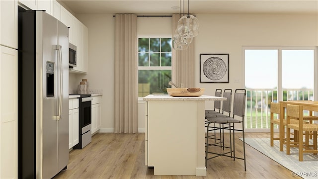 kitchen featuring white cabinetry, hanging light fixtures, a kitchen bar, a kitchen island, and appliances with stainless steel finishes