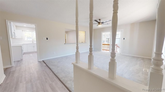 spare room featuring ceiling fan, a healthy amount of sunlight, light wood-type flooring, and a textured ceiling