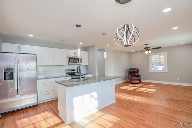 kitchen with light wood-type flooring, white cabinetry, stainless steel appliances, and a kitchen island with sink