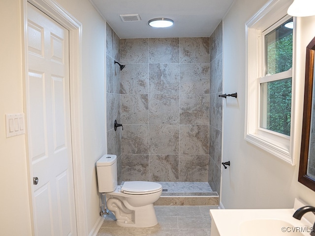 bathroom with tile patterned flooring, plenty of natural light, toilet, and tiled shower