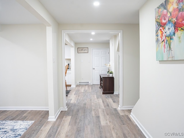 hall with baseboard heating and light hardwood / wood-style flooring