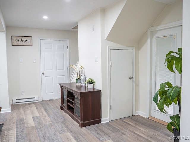 foyer entrance with baseboard heating and light wood-type flooring