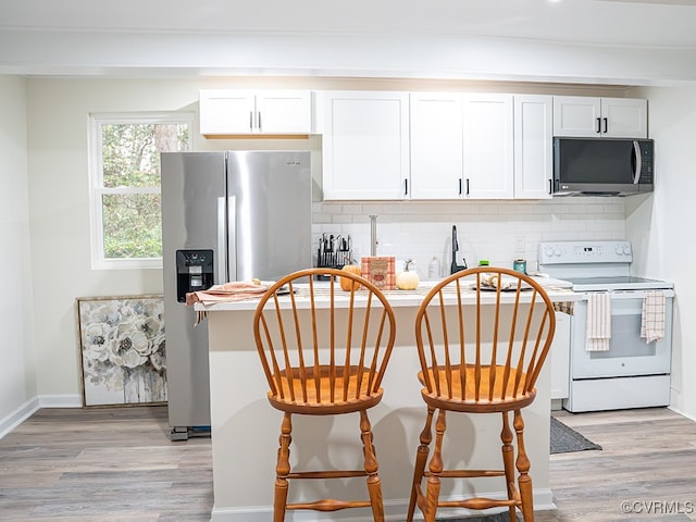 kitchen featuring appliances with stainless steel finishes, light wood-type flooring, tasteful backsplash, and white cabinetry