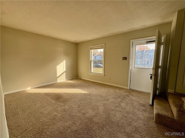 carpeted empty room featuring a textured ceiling and a wealth of natural light