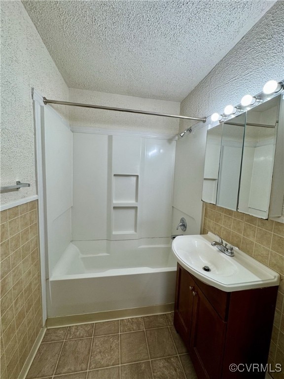 bathroom featuring a textured ceiling, bathing tub / shower combination, tile patterned floors, and tile walls