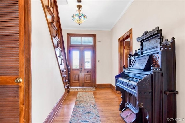 foyer entrance with french doors, light hardwood / wood-style flooring, and ornamental molding