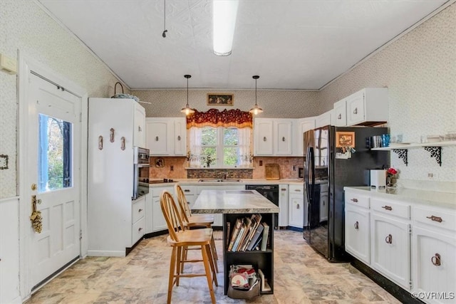 kitchen featuring white cabinetry, a center island, pendant lighting, and black appliances