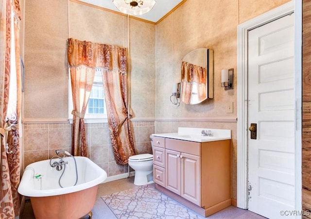 bathroom with tile walls, a bathtub, vanity, toilet, and crown molding