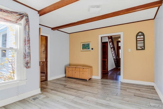 unfurnished room with beam ceiling, ornamental molding, and light hardwood / wood-style floors