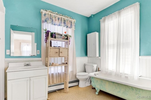 bathroom featuring vanity, a baseboard heating unit, toilet, and a tub to relax in