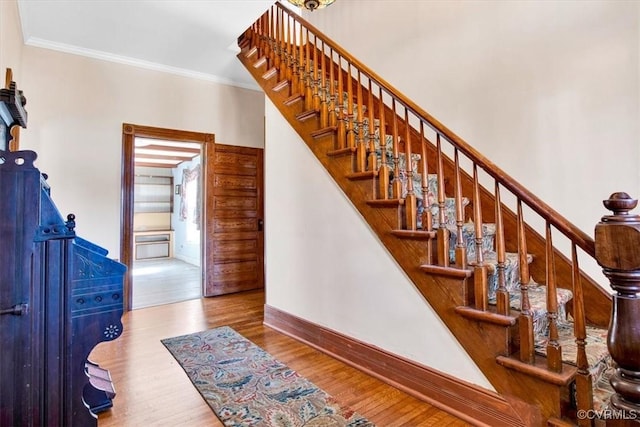 stairway with crown molding and hardwood / wood-style floors