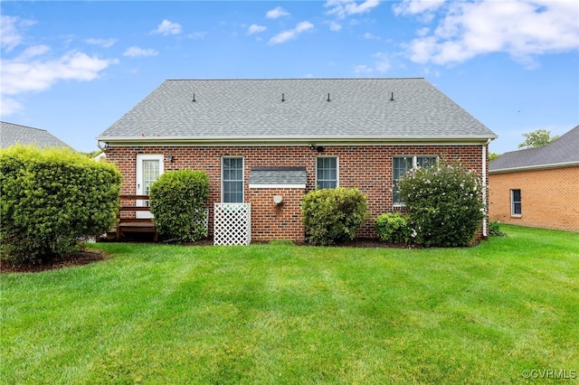 back of house featuring a lawn, brick siding, and a shingled roof